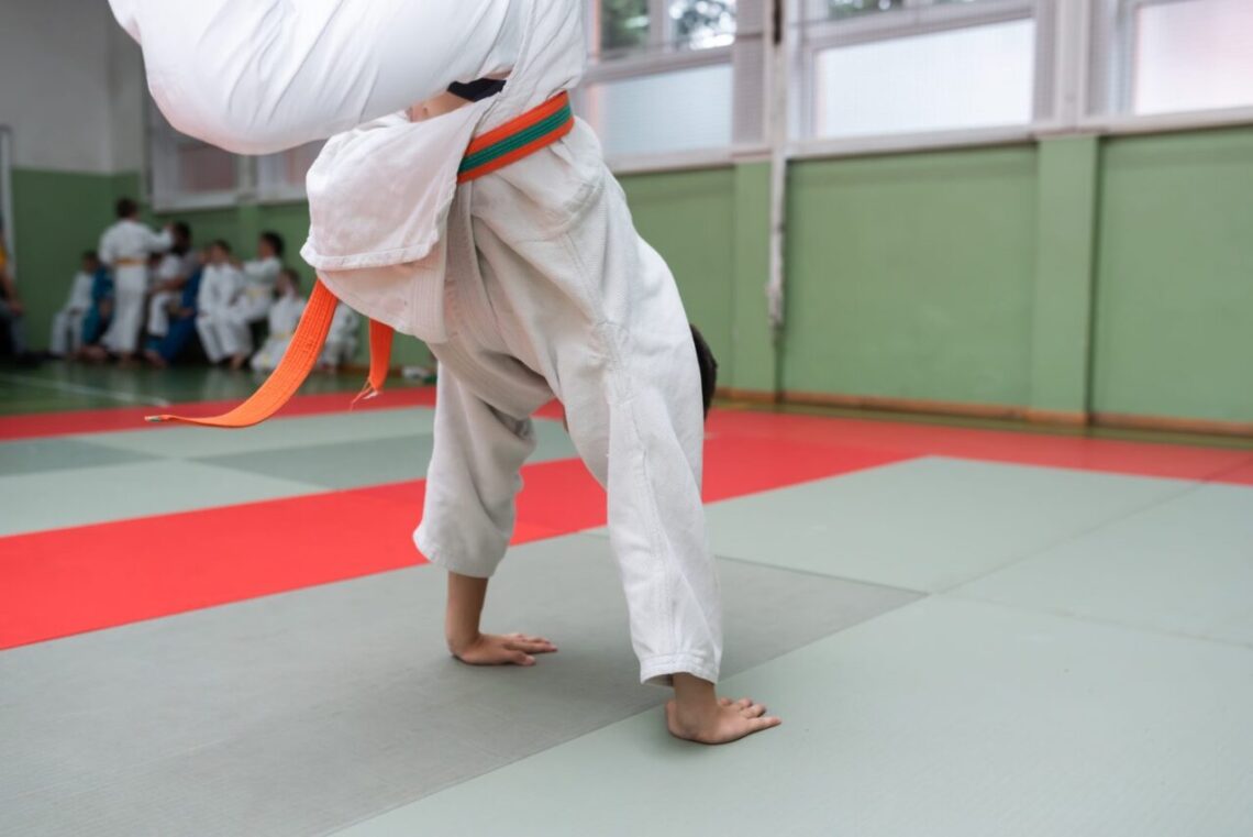 Deux judokas s’entraînent à exécuter une prise de judo sur un tatami.