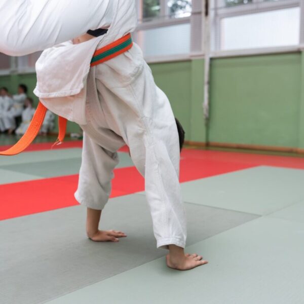 Deux judokas s’entraînent à exécuter une prise de judo sur un tatami.